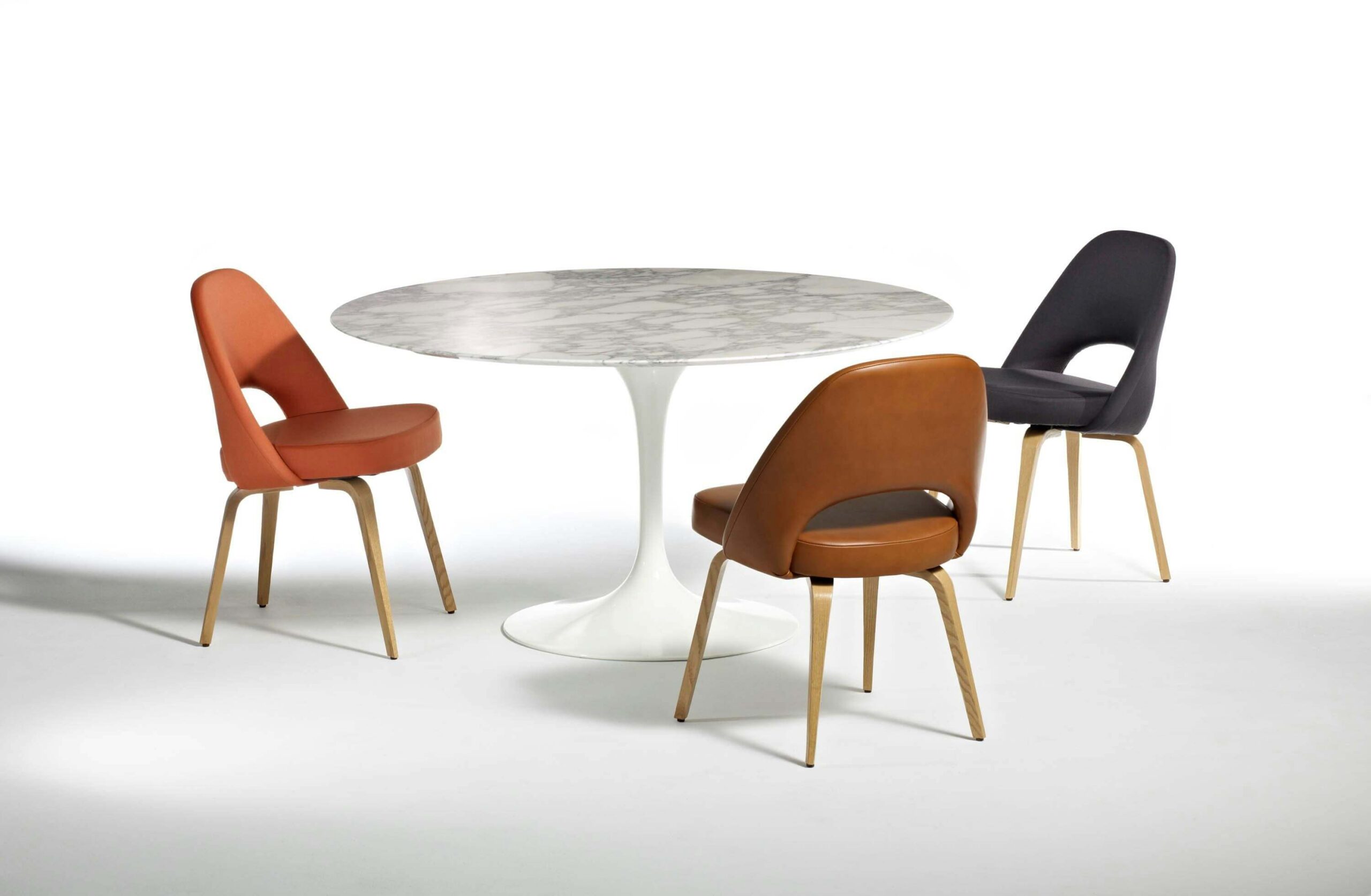Saarinen Round Table in a white room with three leather chairs