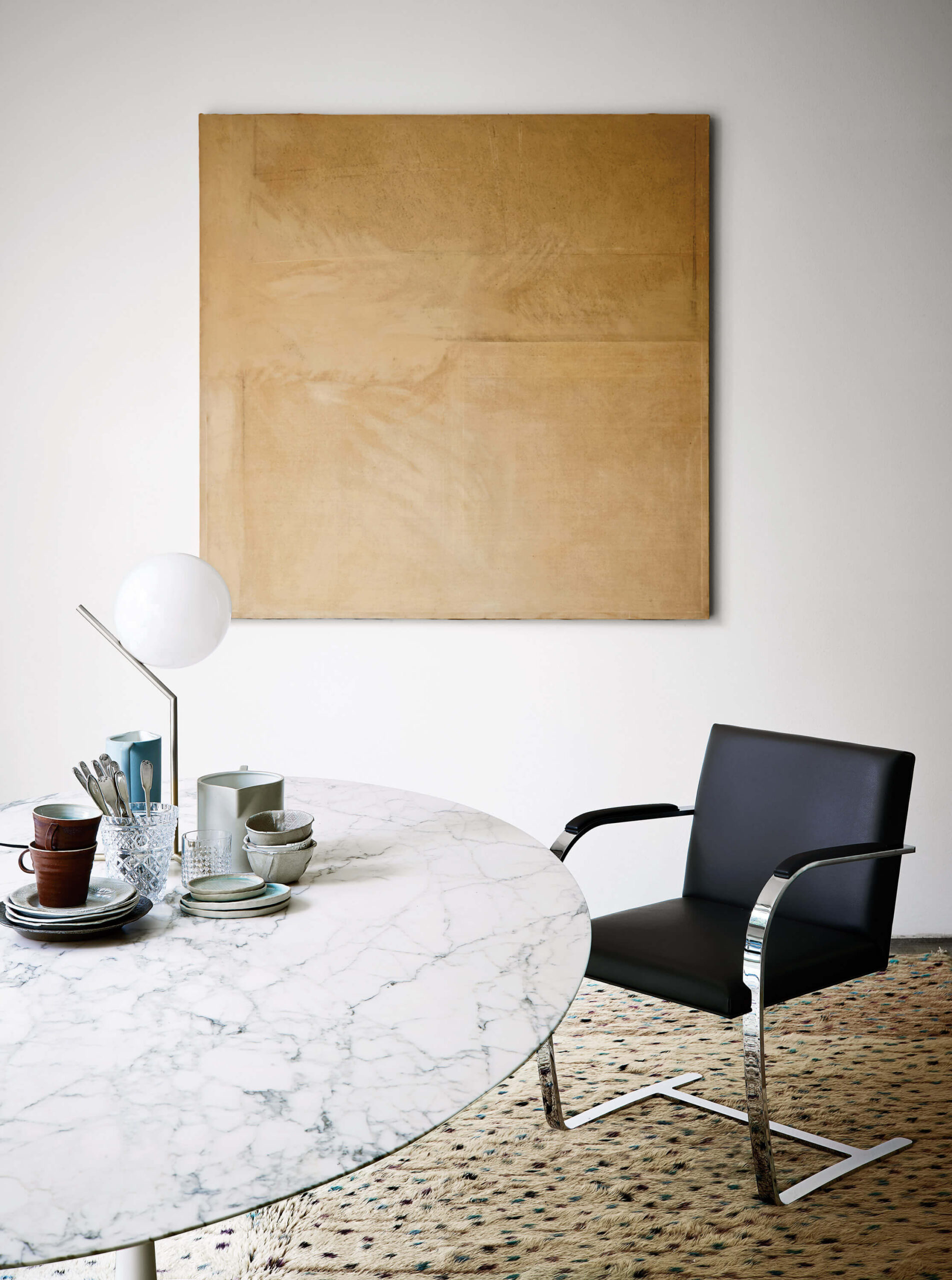 Saarinen Round Table at a white room with a black leather chair