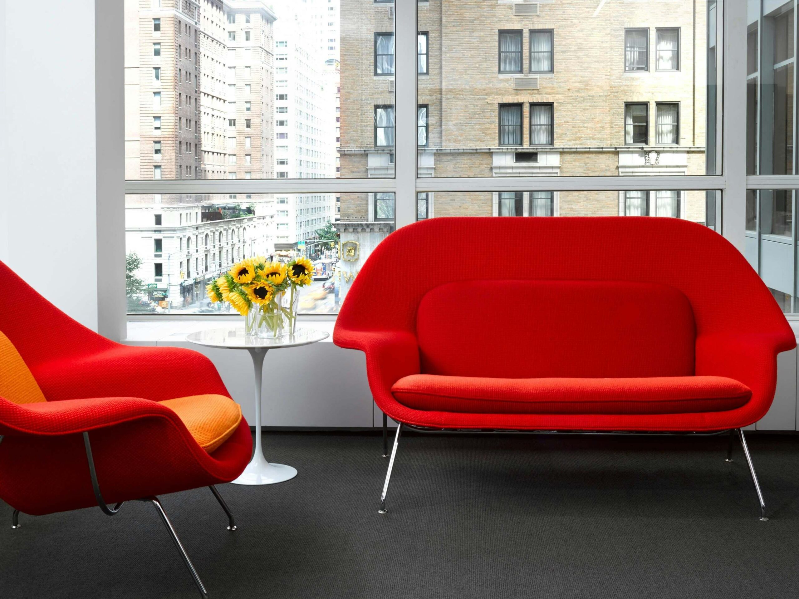 Saarinen Side Table next to a red sofa in a city office