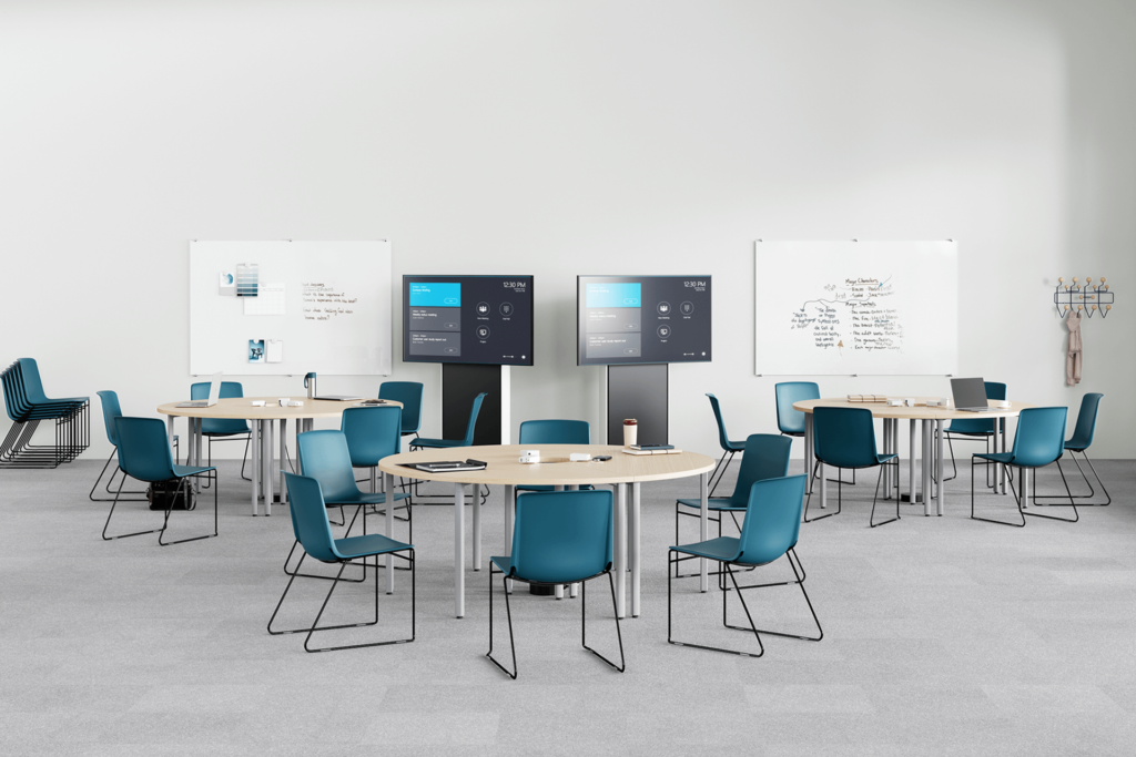 university classroom deaturing blue chairs and three rounded tables