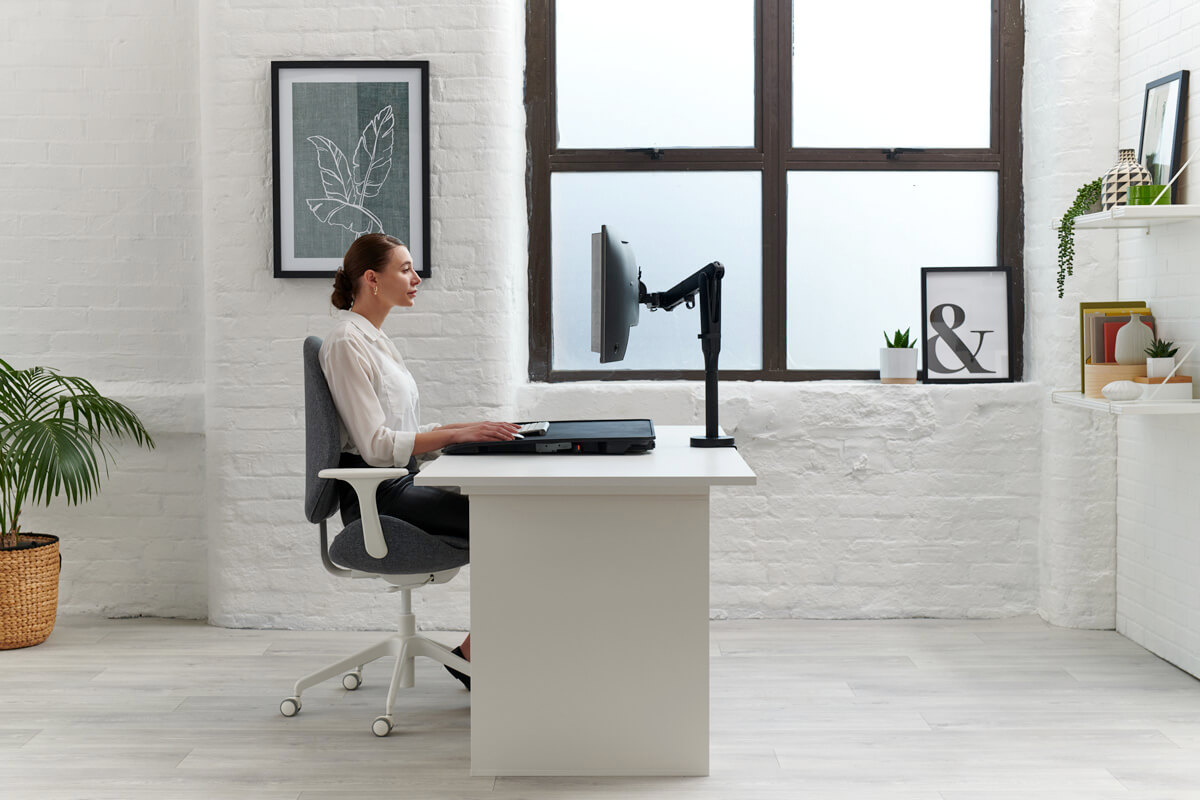 Monto Sit to Stand Desk Riser side detail with a person sitting in front