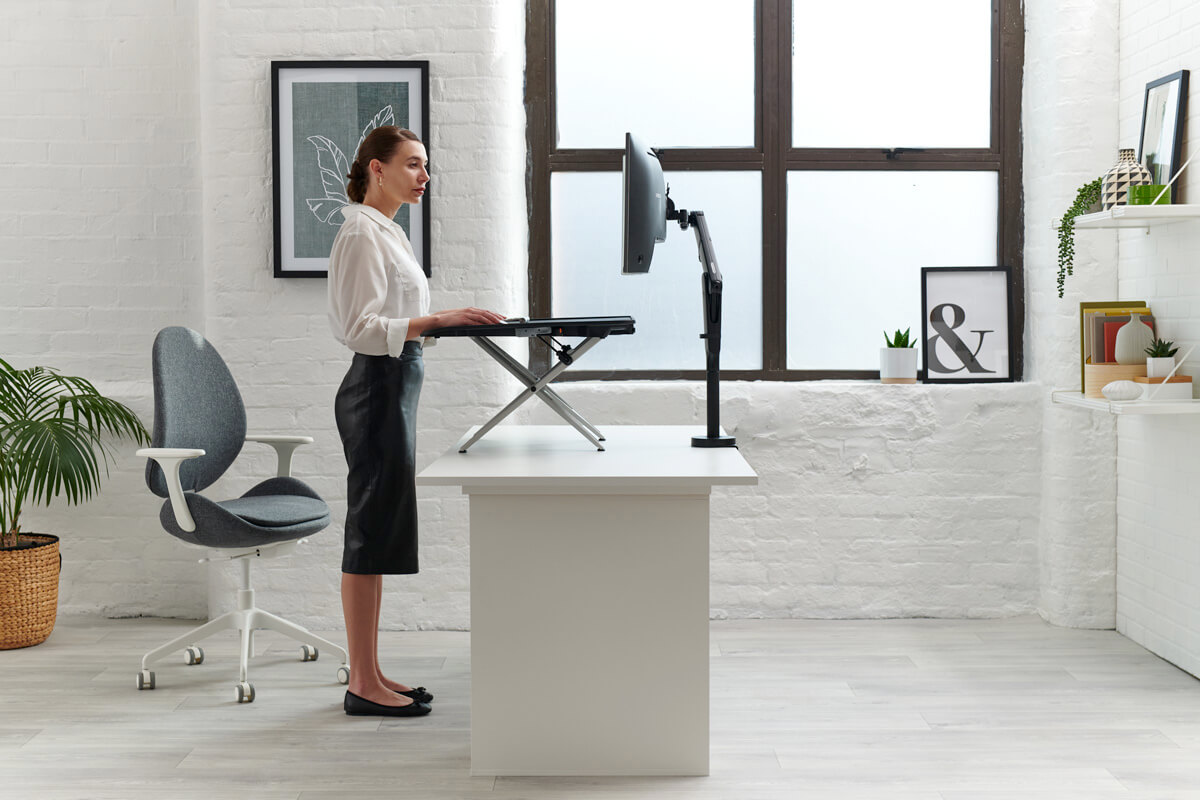 Monto Sit to Stand Desk Riser side detail with a person standing in front
