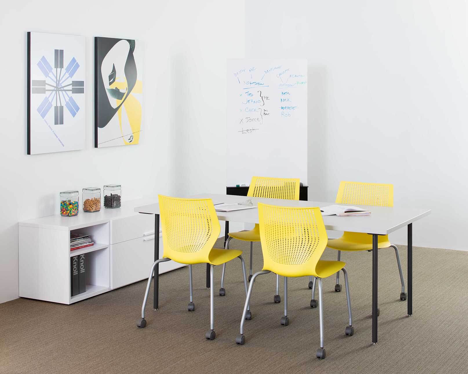 a mdoern white meeting room featuring four yellow MultiGeneration Stacking Chairs wround a white meeting rectangular table