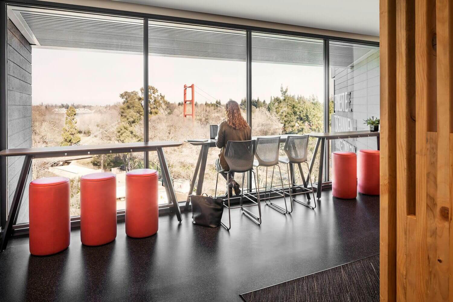 MultiGeneration Barstool Chair by Knoll next to a big windown and a person sittion facing the streets on a high bench