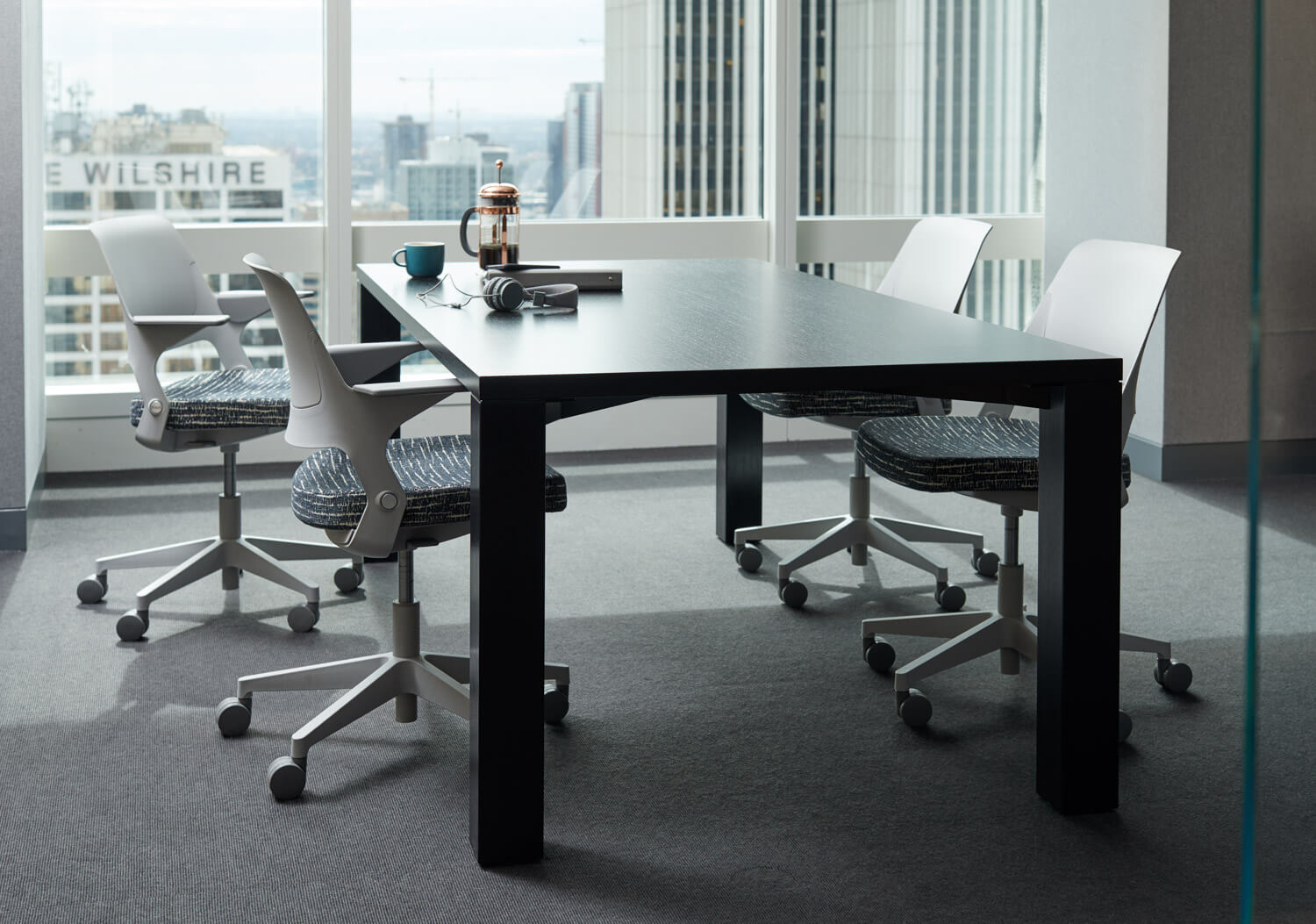 vour Ollo Side Chairs in a small meeting room around a brown wooden rectangular table in a glass office next to a big windows