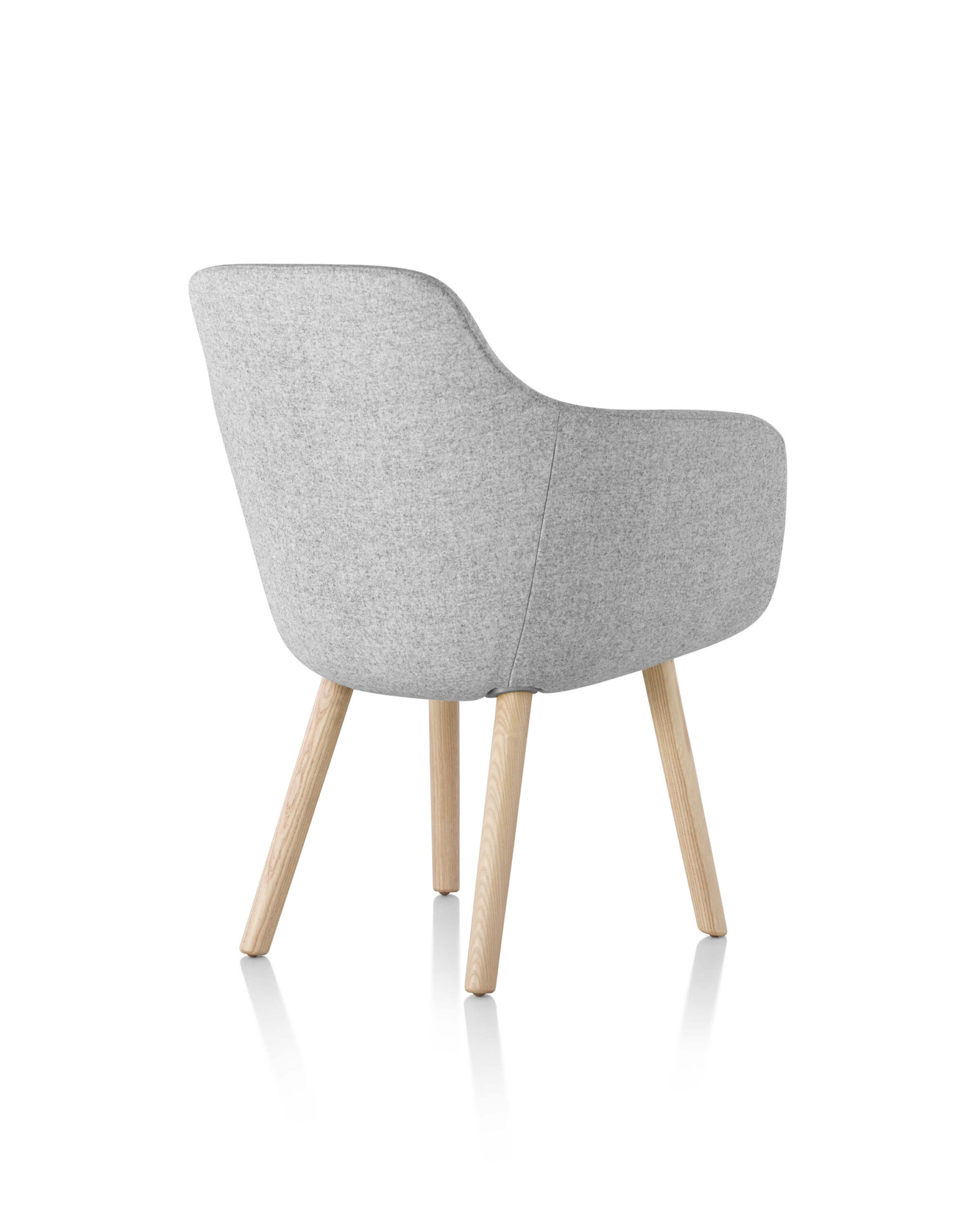 the back side angle of a Saiba Side Chair with green upholstery and wooden legs in a white room