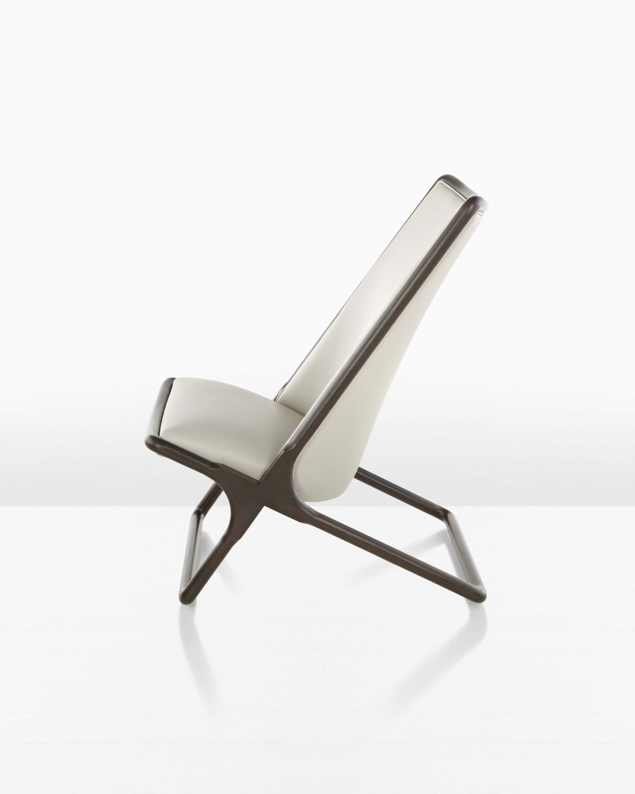 the right side angle of a Scissor Lounge Chair with cream upholstery and dark oak wooden frame in a white room