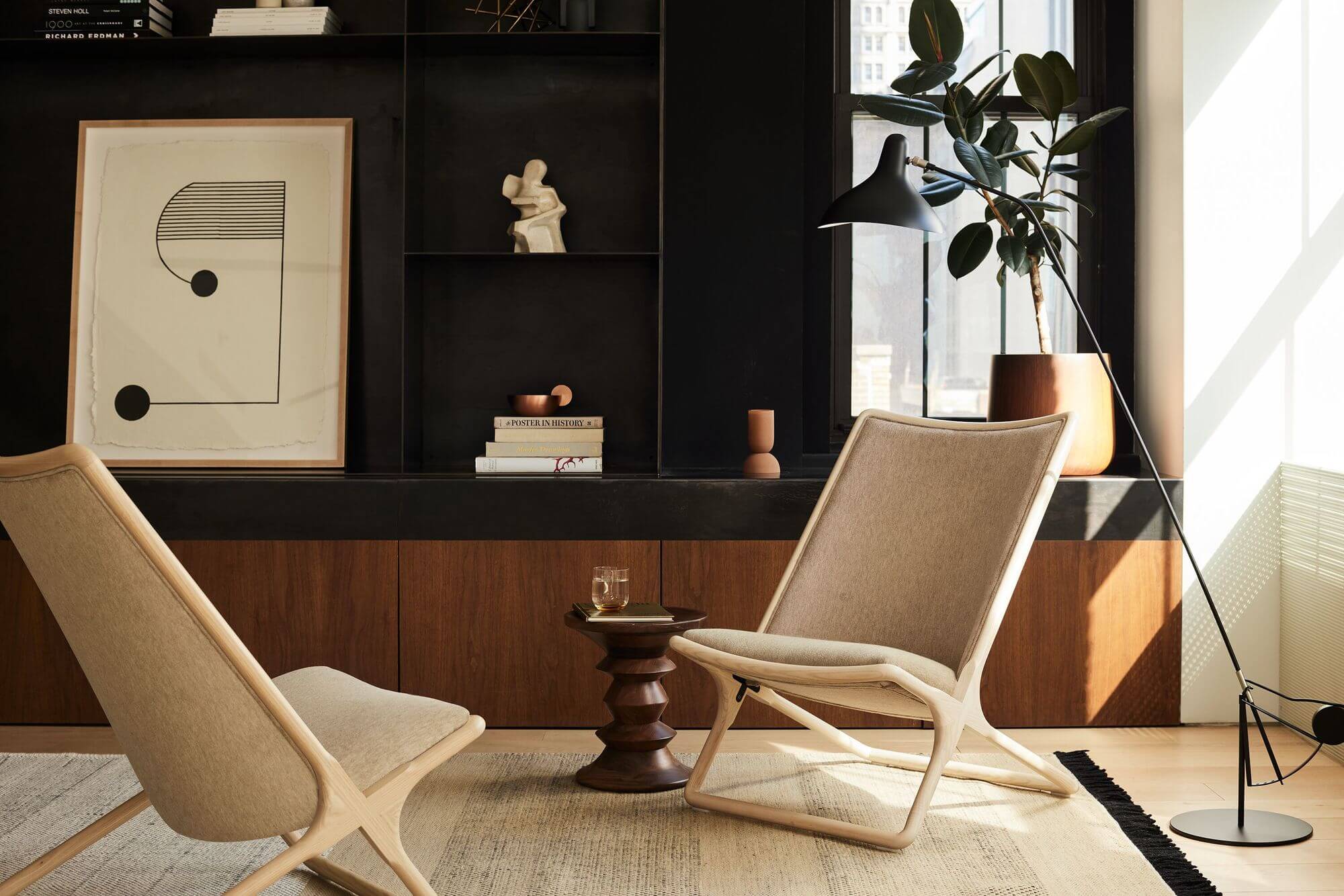 two cream Scissor Lounge Chairs in a modern space with wooden storage furniture in the backgorund and a minimalistic painting