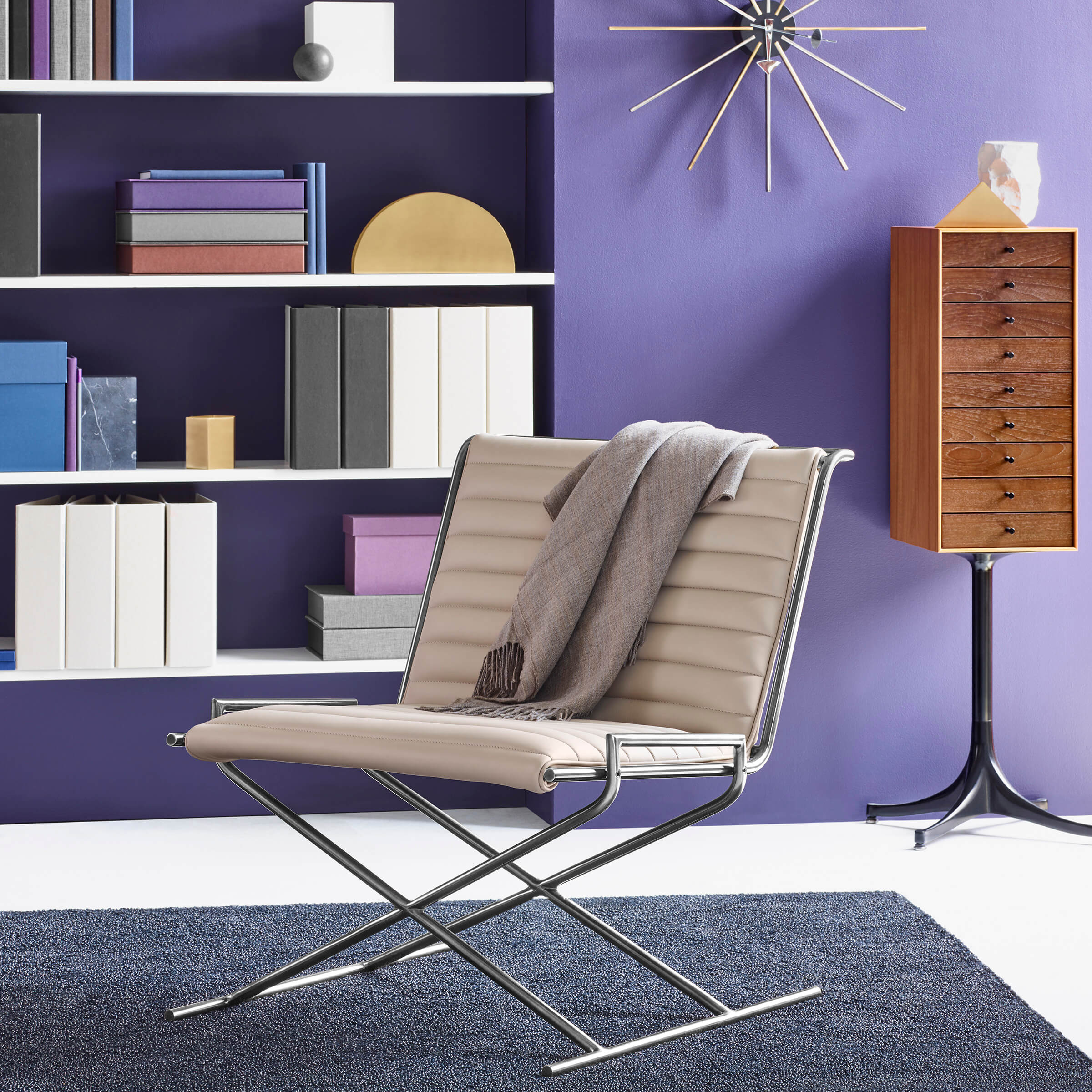a modern space featuring vibrant colours and a coloured bookhelf in the background with a Sled Side Lounge Chair with cream leather