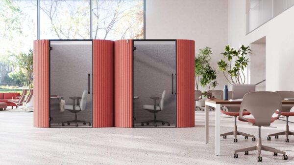two bay work pods with red exteriors and two asari chairs inside next to a meeting table with green zeph chairs