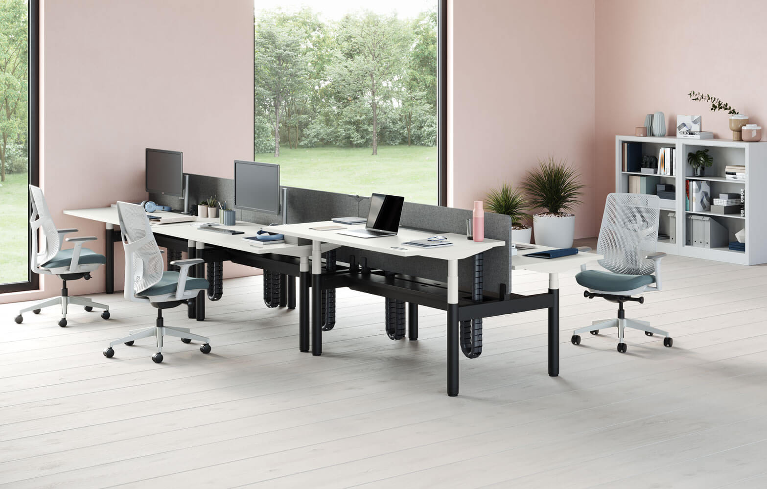 sit to stand workstations in a modern office designed to fosted Activity-Based Work, next to two big windows and abookshelf in the background.