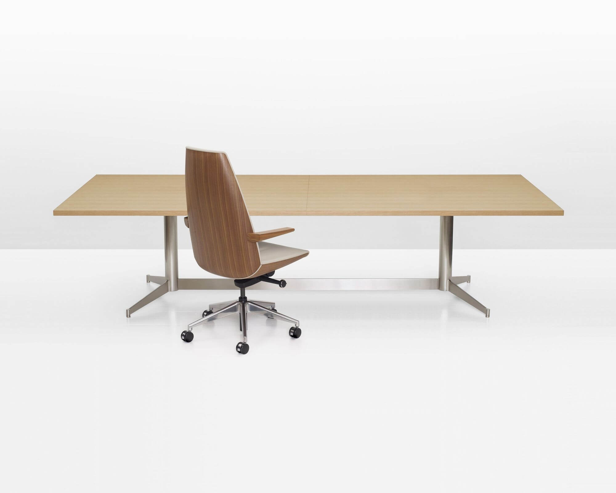 the side angle of a wooden top MP Conference table with polished aluminium legs in a white room and a wooden back executive office chair.