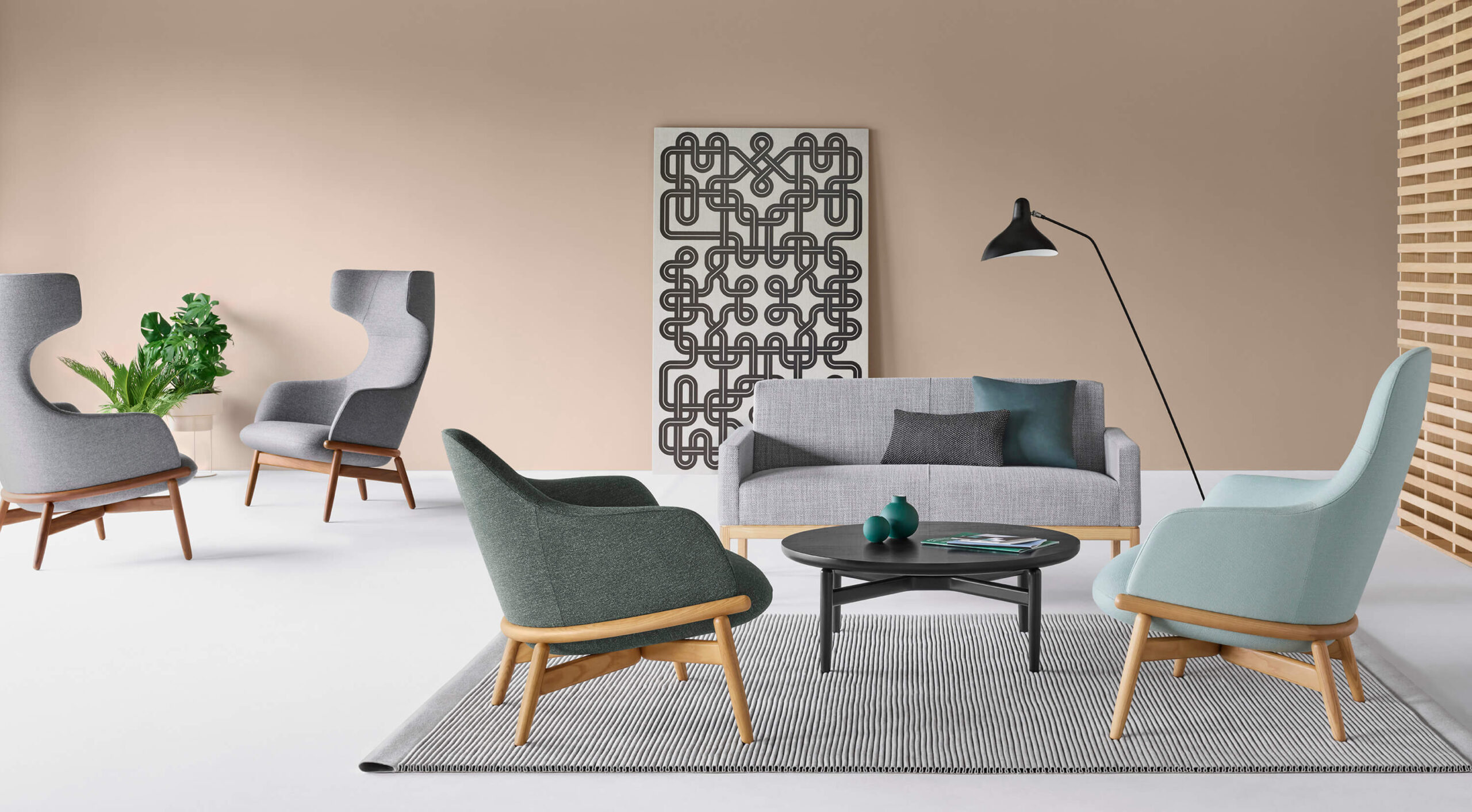 a modern lounge area featuring modern side chairs and a black wood reframe side table in the middle with an abstract painting in the background
