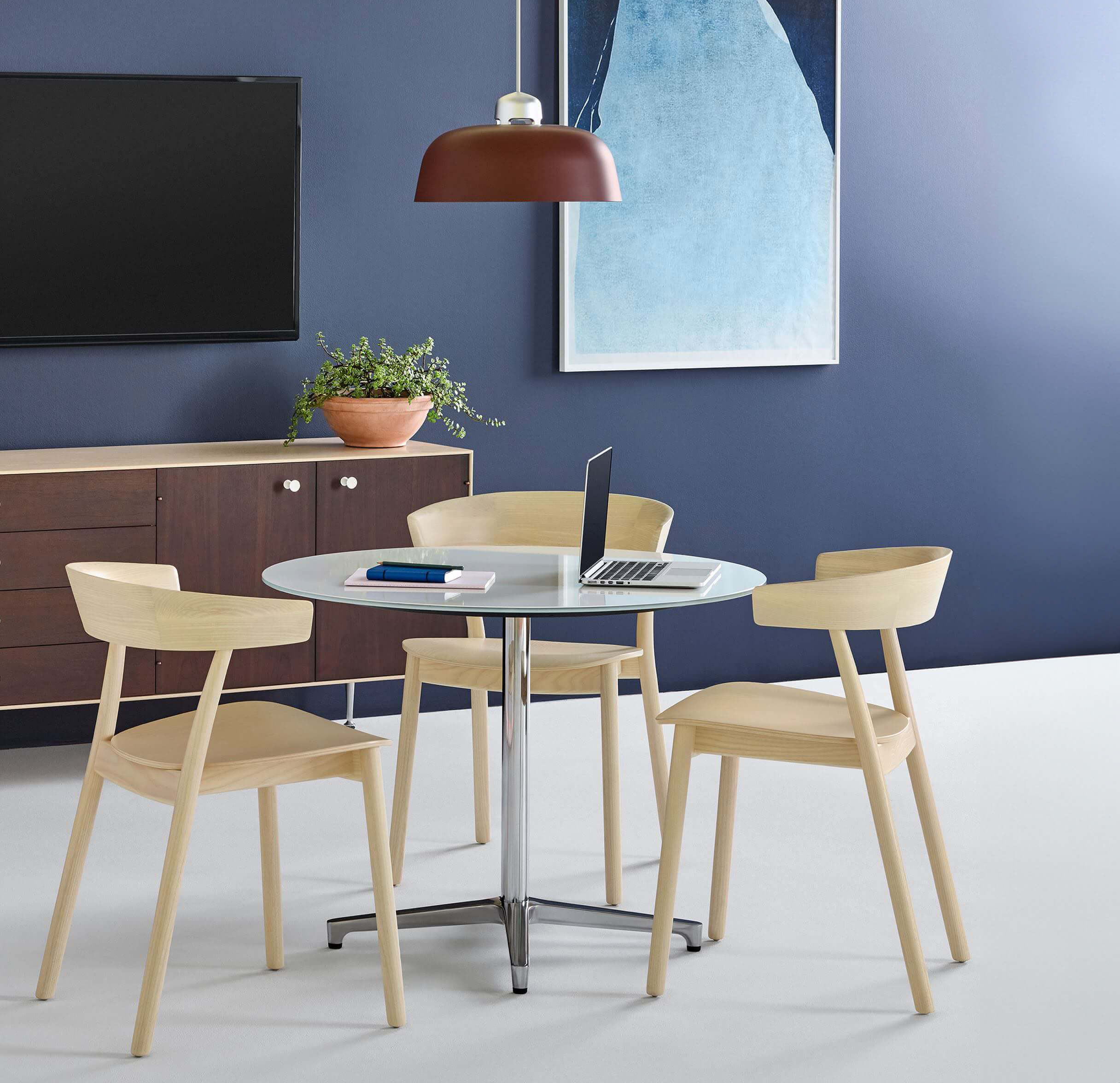 marble top and polished metal base saiba dine table, in a minimalistic room with a laptop on top surrounded by 3 wooden chairs