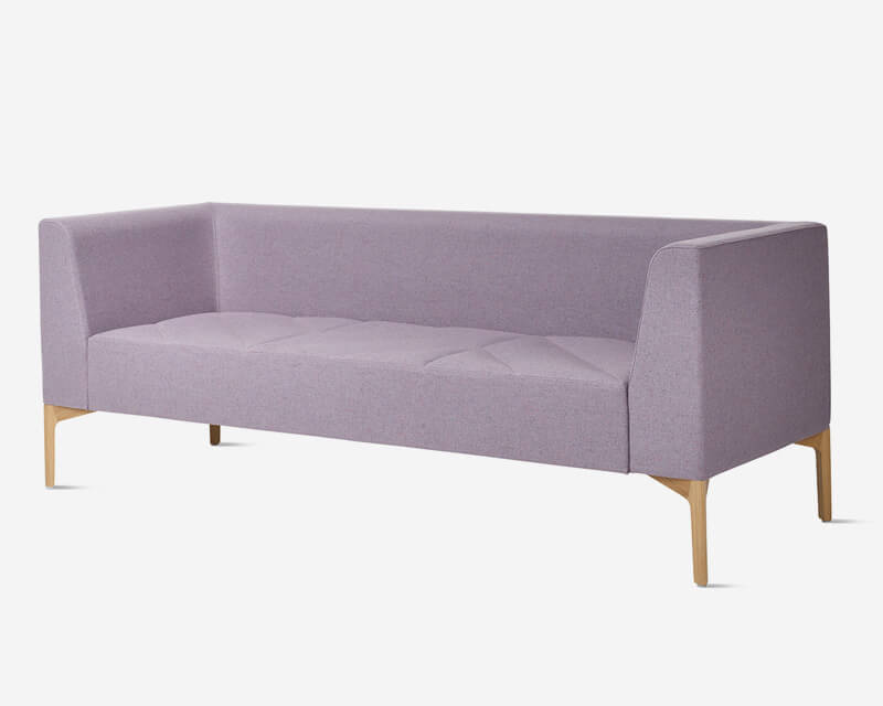 the front side angle of a three seat Hatch Modular Sofa with arms and wooden legs on a white room
