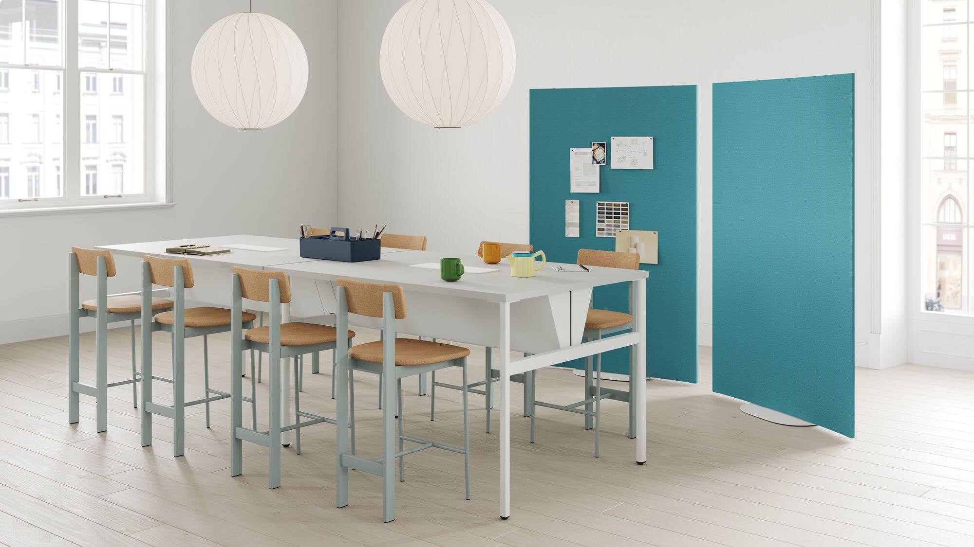 a modern space featuring a tall white table and eight Betwixt Wooden Barstools around with two linght blue panels in the background