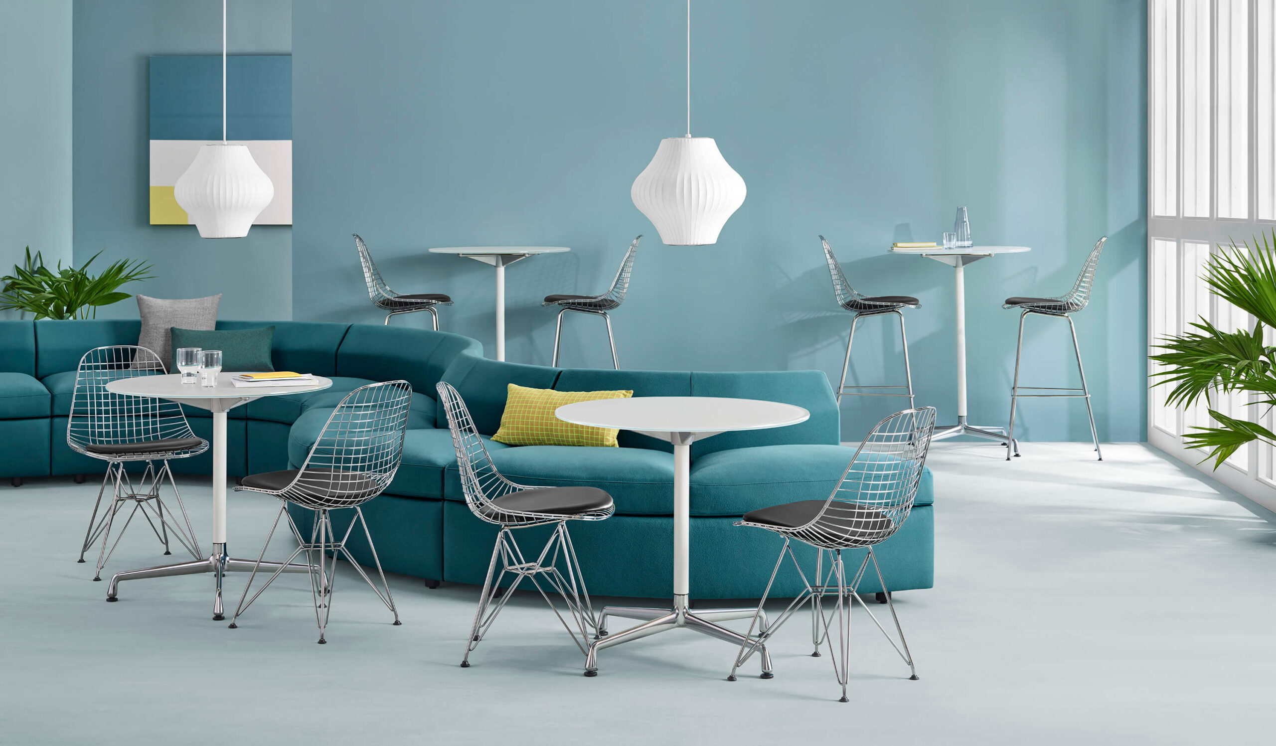 a gray S shapped Bevel Modular Sofa Group in a modern office room with two side tables and for wired chairs around