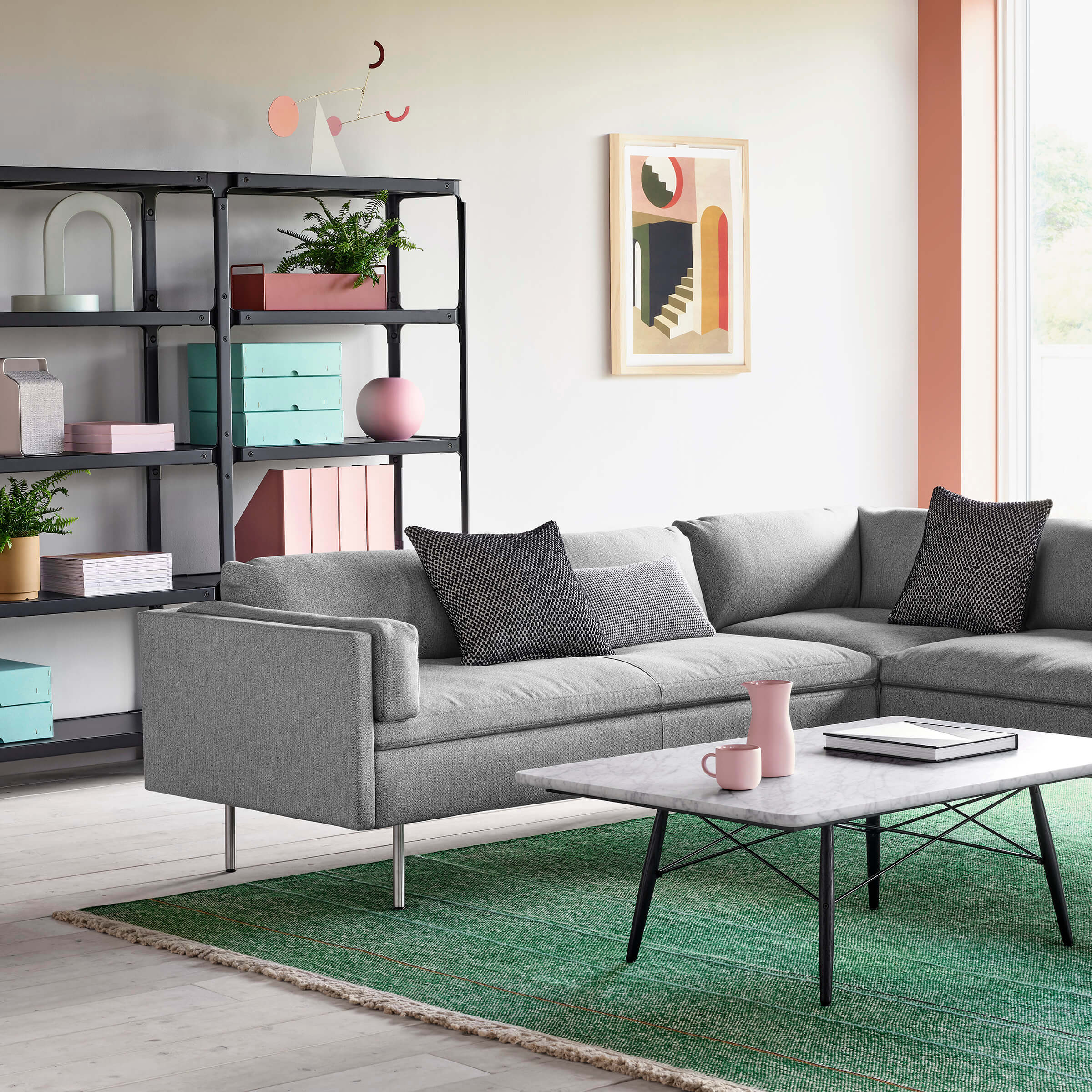 the corner detail of a modern lounge area with an L shapped Bolster Sofa Group in grey colour and a coffe table in front of it
