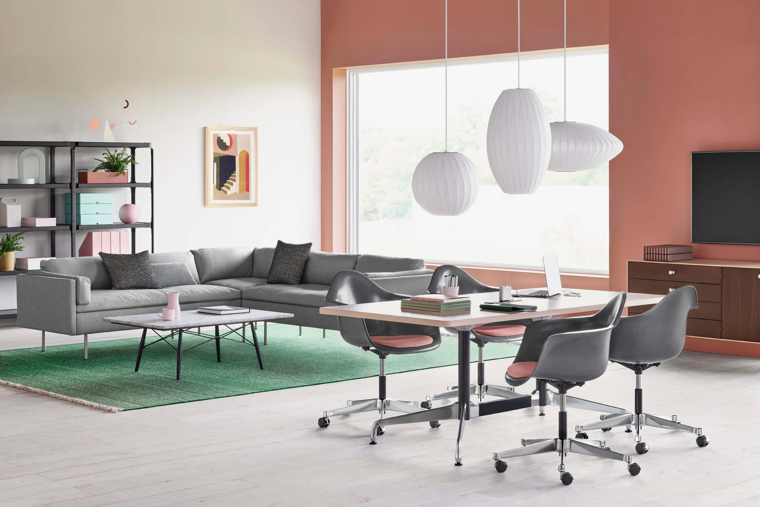 a modern lounge area with an L shapped Bolster Sofa Group in grey colour and a small meeting table with four side chairs in front next to a tv with an storage cabinet
