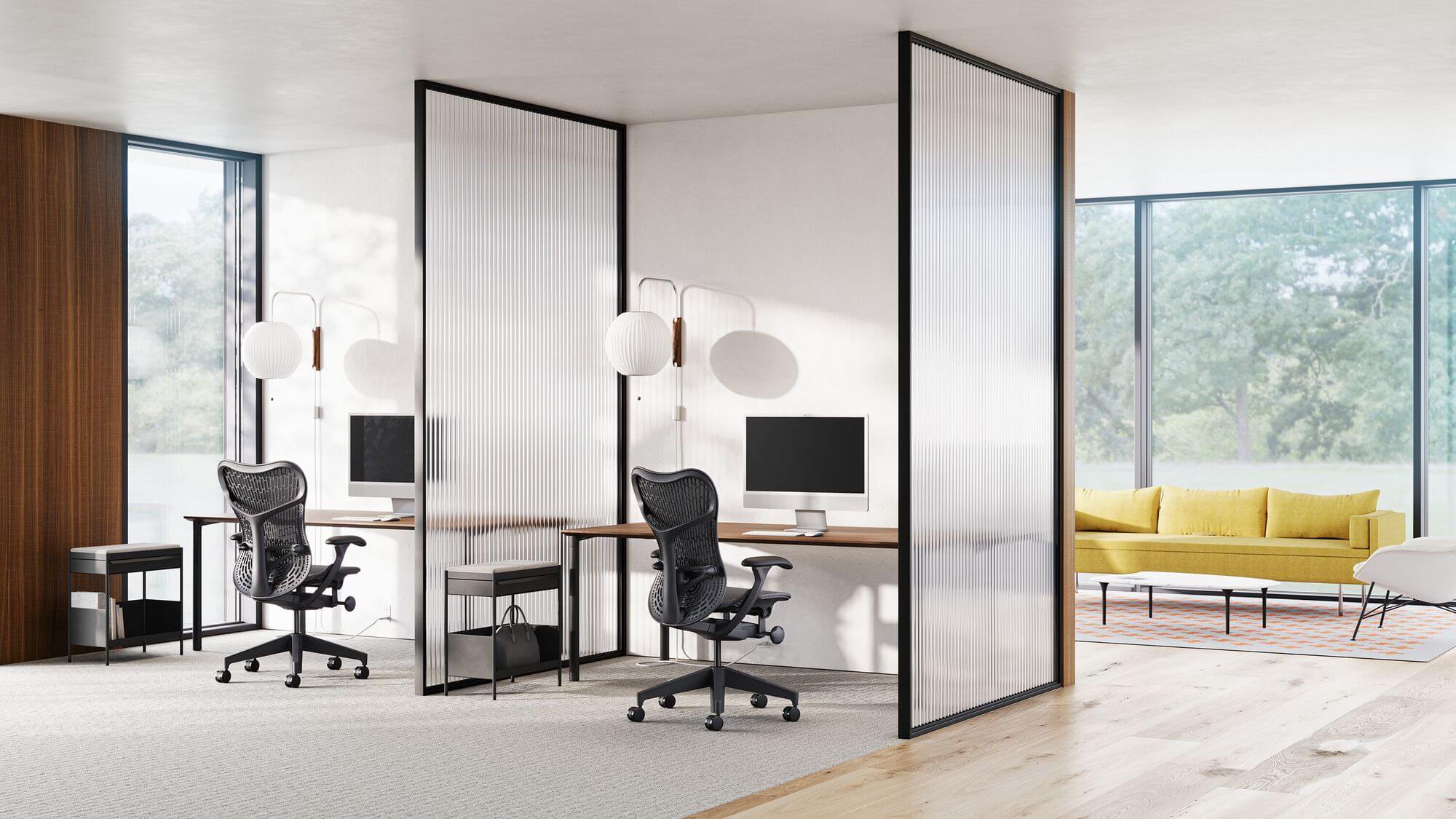 a modern office space with two workstations and a Bolster Sofa Group in yellow upholstery next to a tall window