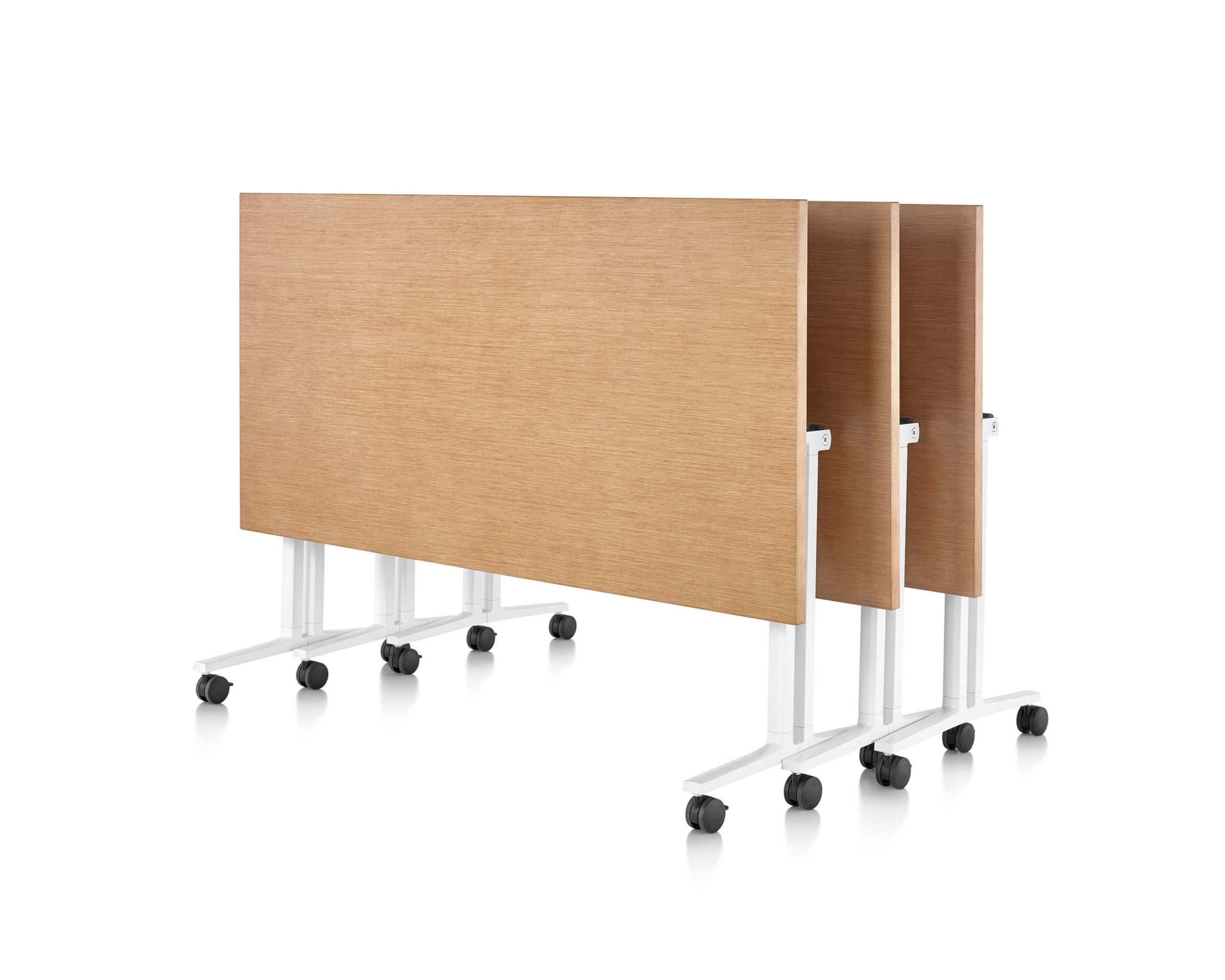 three wooden top vertically folded Everywhere Multi-Purpose Tables stacked in a white room