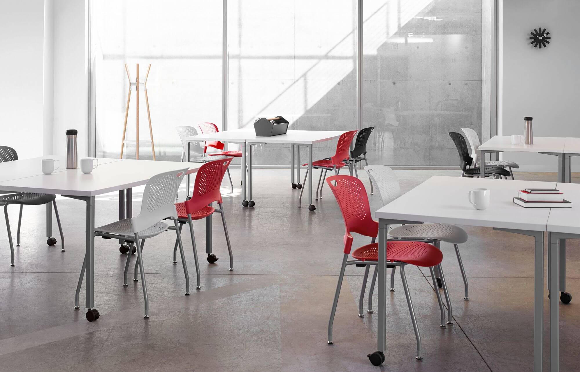 a modern white classroom with concrete walls featuring four groups of student chairs and Everywhere Multi-Purpose Tables and a whiteboard in the right side