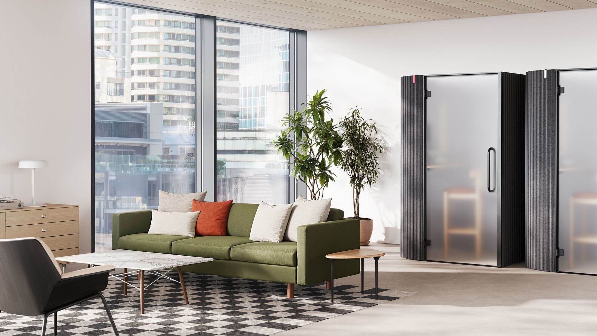 a modern office lounge space featuring modeern furniture with two soundproof pods in the right side and a small seating area with a sofa a coffe table and a lounge chair in the left side with a Nelson Basic Storage Cabinet Series, a big window behing