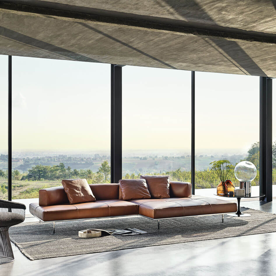 a modern and cozy living room featuring an L shapped with leather upholstery matic sofa in the middle side chair and a big panoramic window in the background