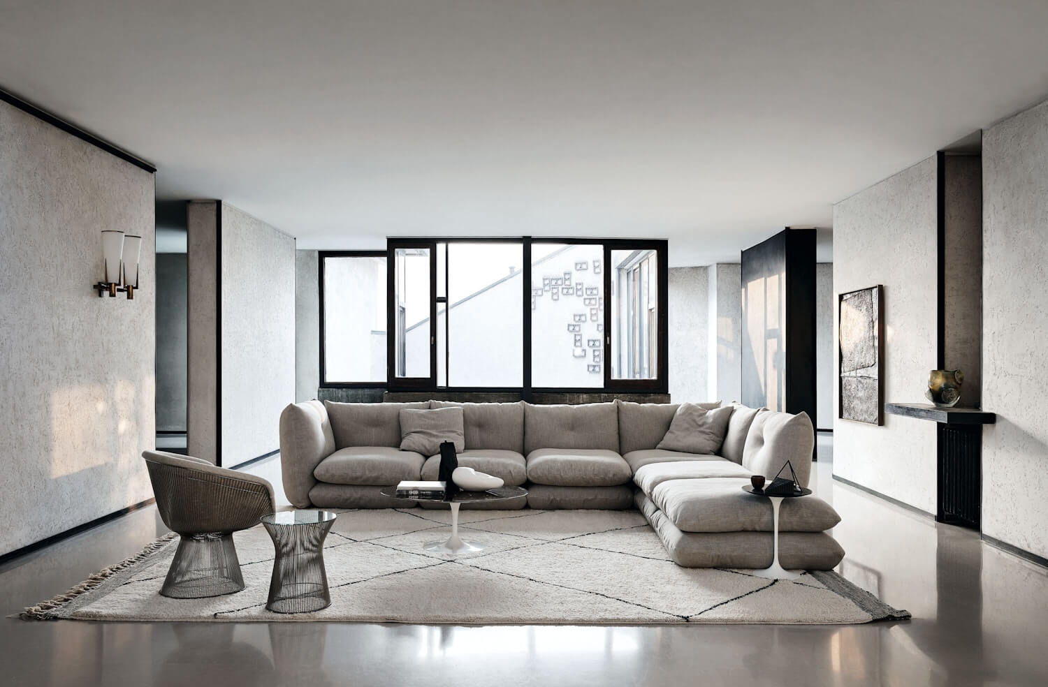 the front side of a modern lounge area featuring designer lounge chairs and side tables awith a big window in the background and a perron pillo sofa by knoll in the middle