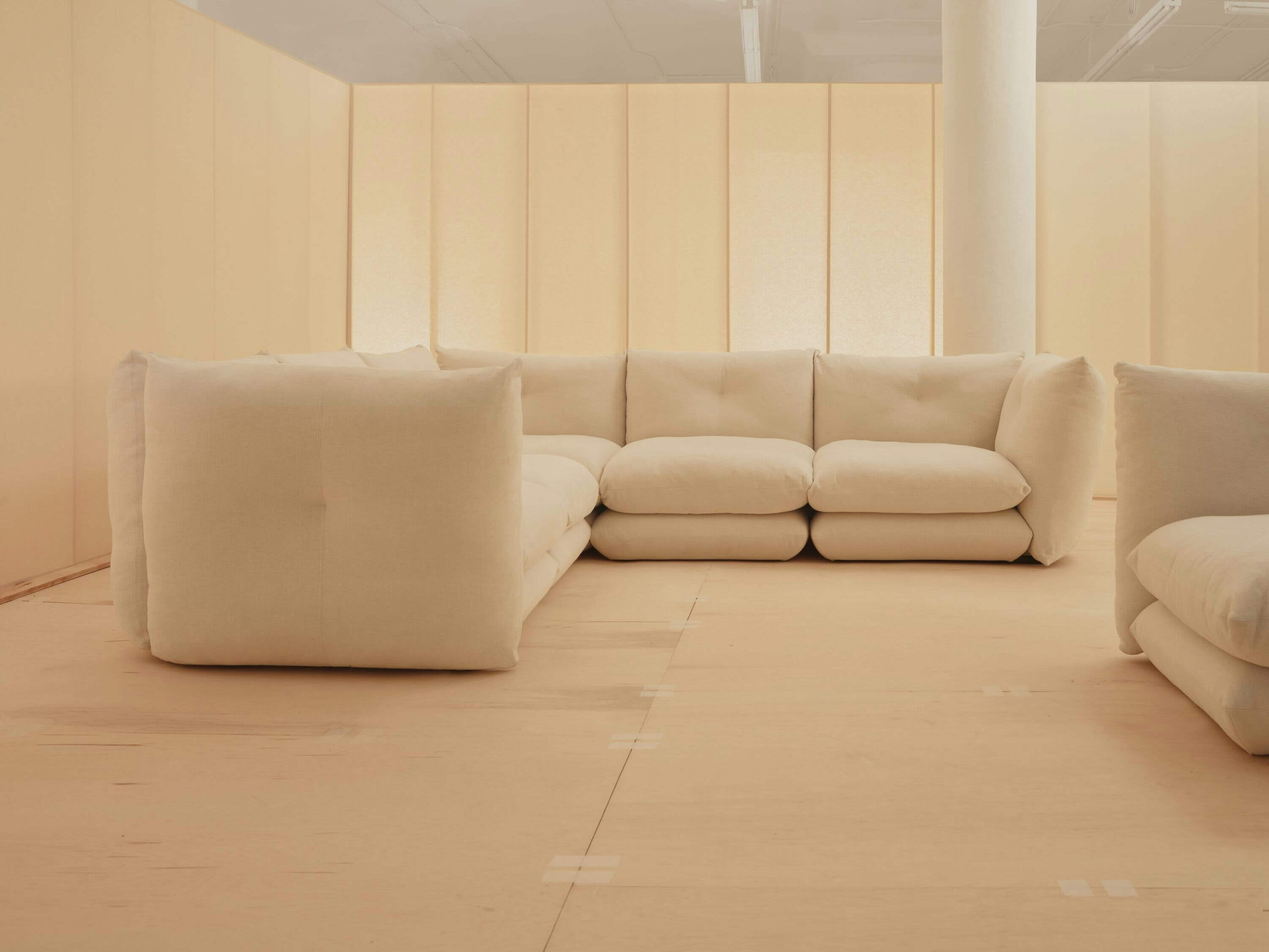 the left side view of an L shapped perron pillo sofa in a room with warm lights