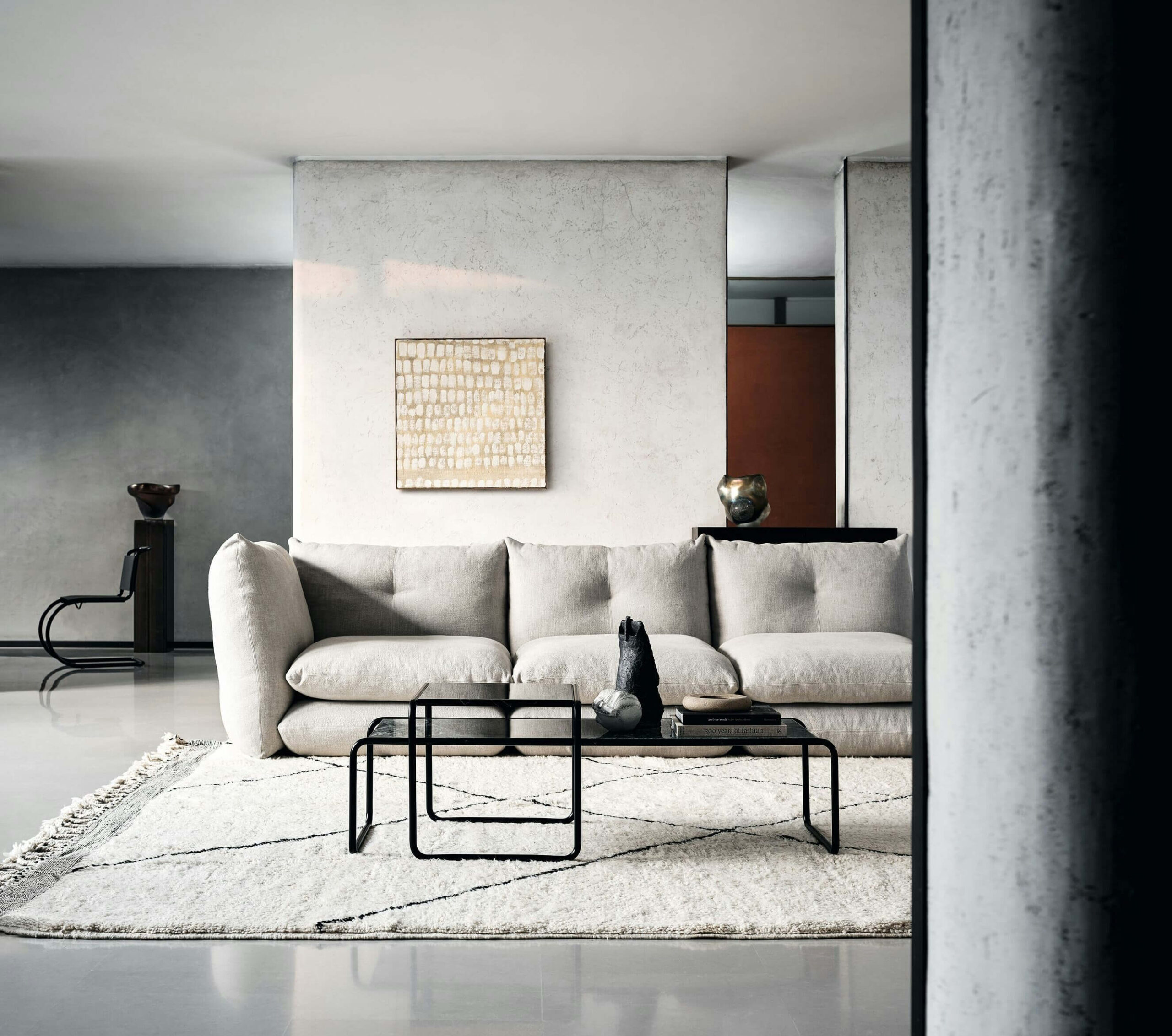 a modern living room featuring a perron pillo sofa by knoll with a black coffee table and a minimalistic pain in the background