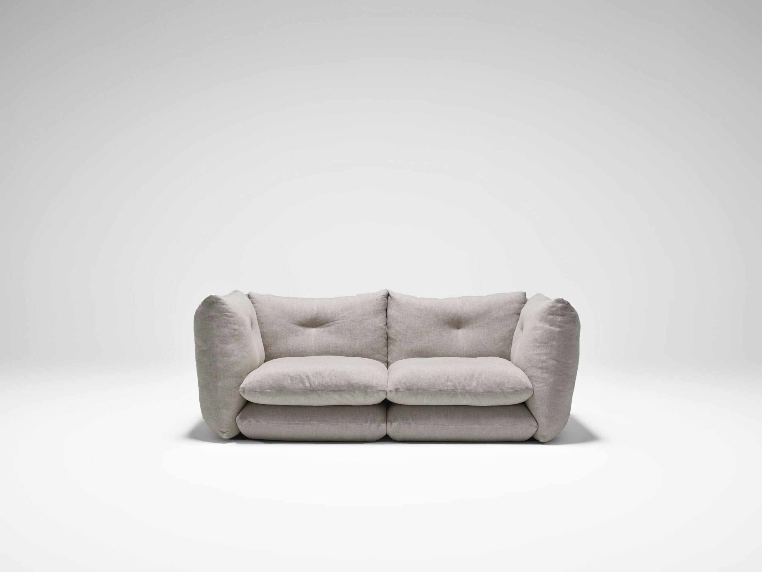 the front side of a two seat perron pillo sofa by knoll with light gray upholstery in a white room