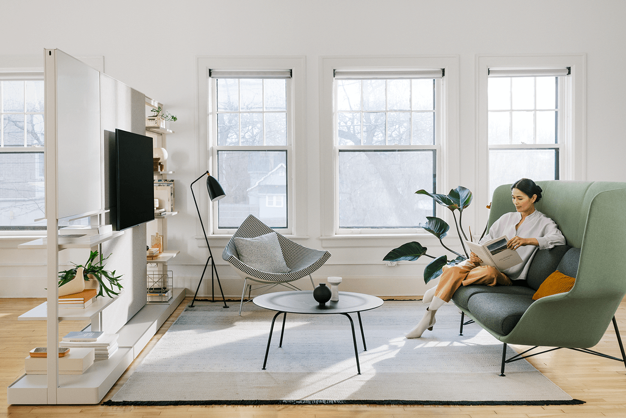 a modern office shared space featuring modern furniture with a tall back sofa and a coconut chair in the backgroudn next to three tall windows