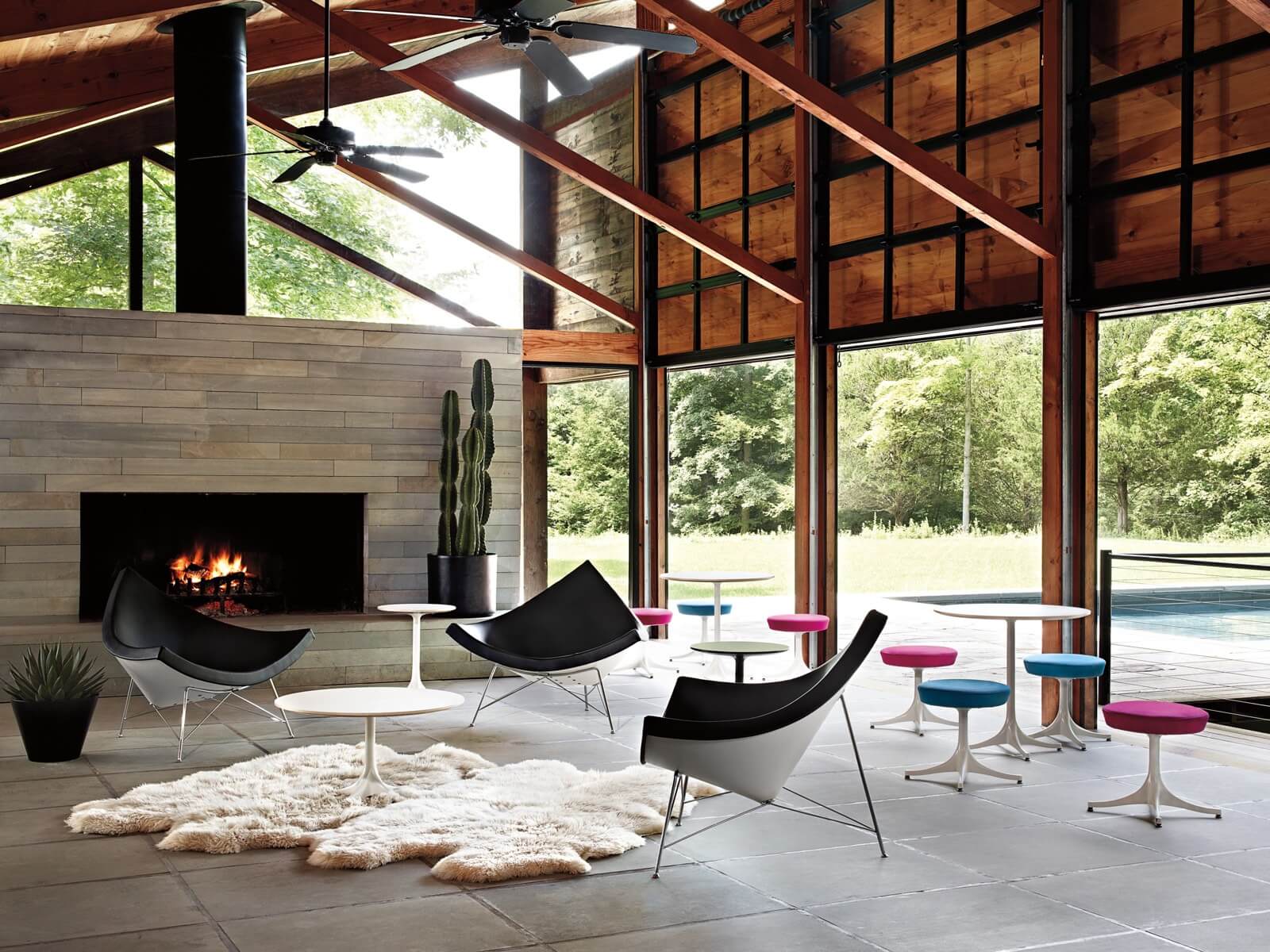 a coconut chair in a modern space with a fire pit in the background a wooden seeling and side stools on the right side