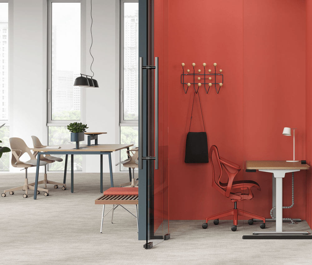 a modern office in sydney featuring a red wall in a private space and a shared desk with a white room in the background