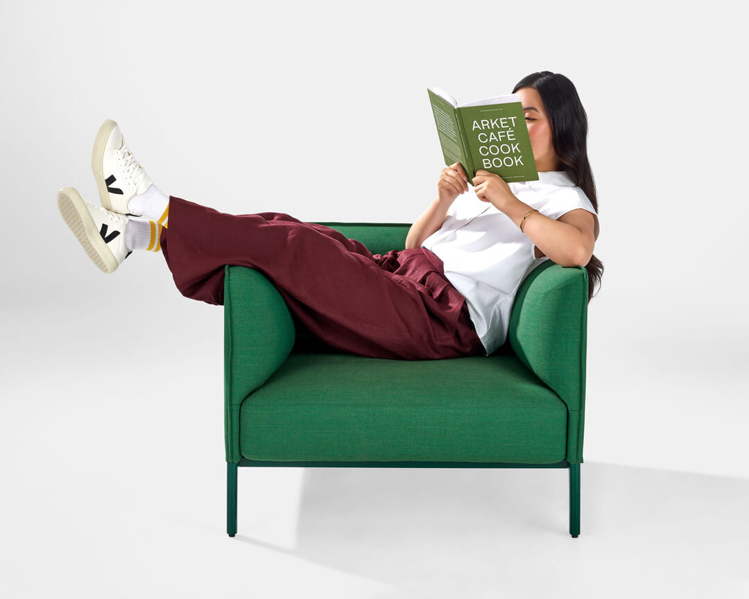 a woman reading seating on a green mimo lounge chair by naughtone in a white room