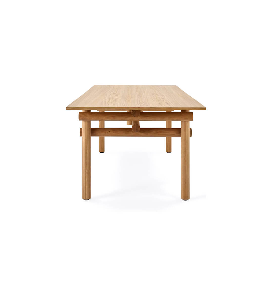 the left side of a wooden Muecke dining table by knoll in a whte room