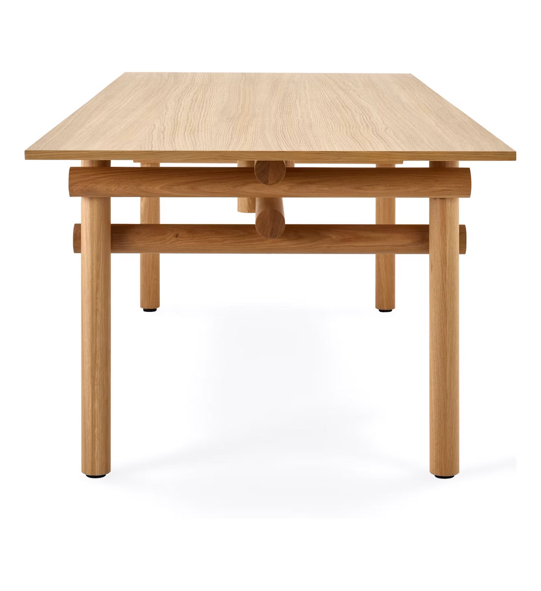 the left side of a wooden Muecke dining table by knoll in a whte room